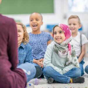 A group of children smiling and listening to an adult