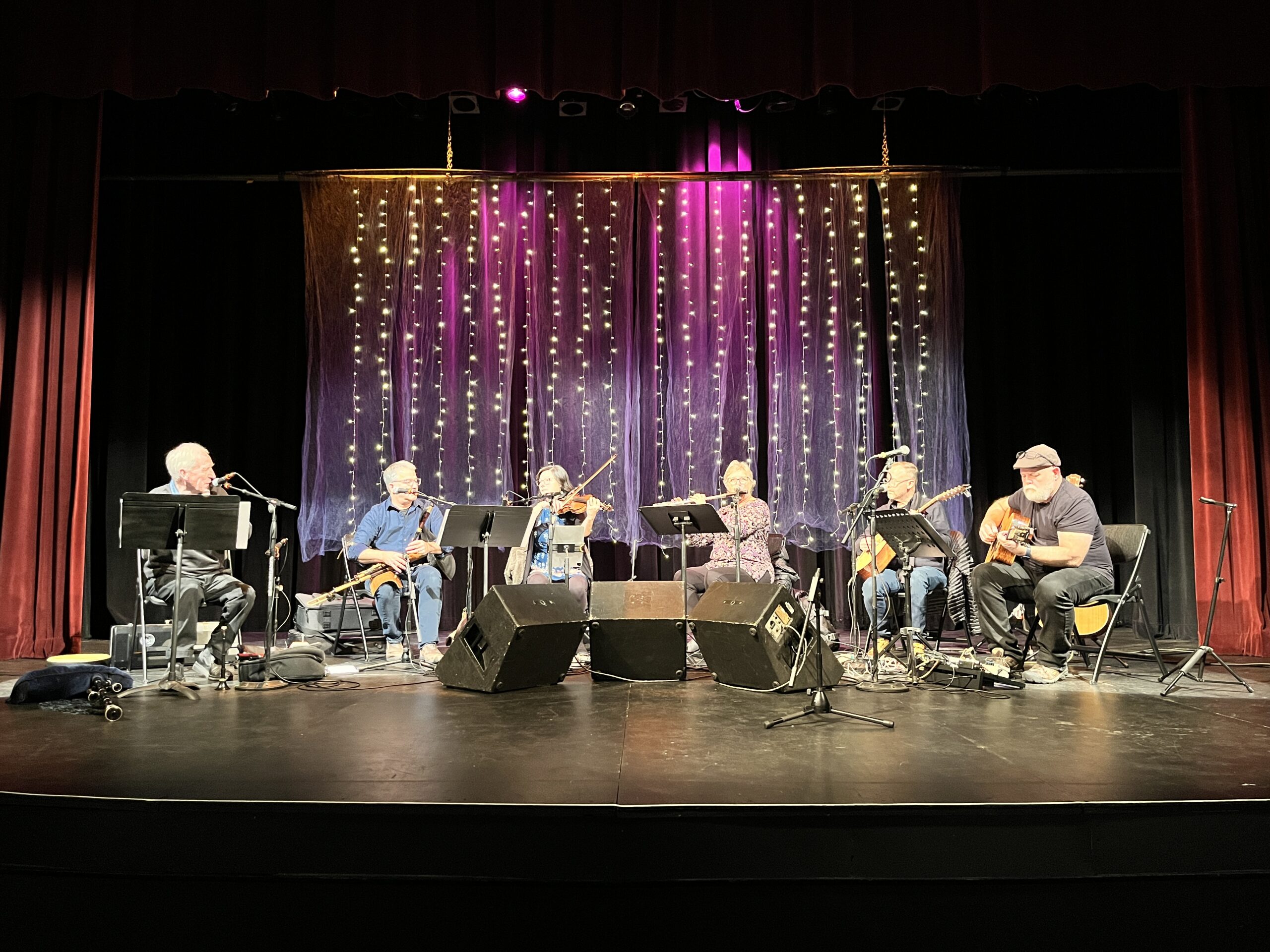 A band with 6 musicians playing on a stage.