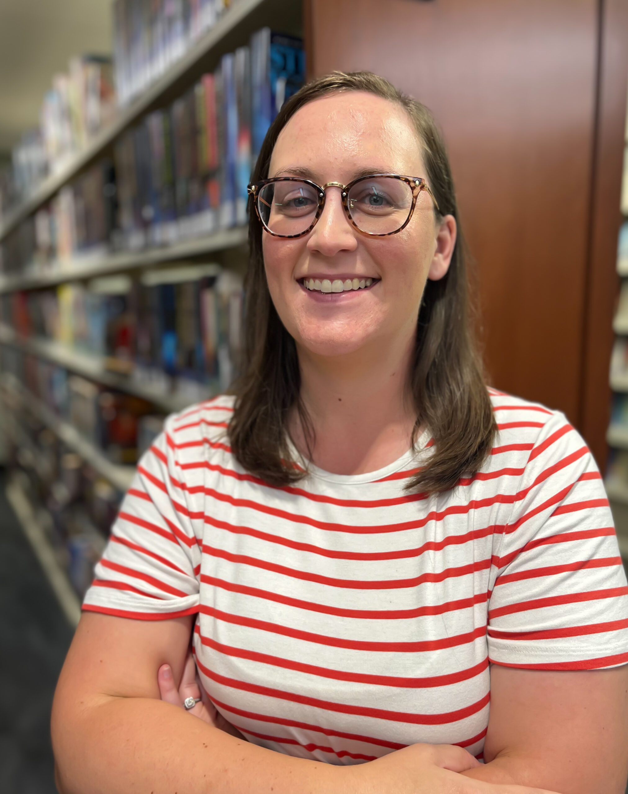 Woman with brown hair and glasses with red and white striped shirt