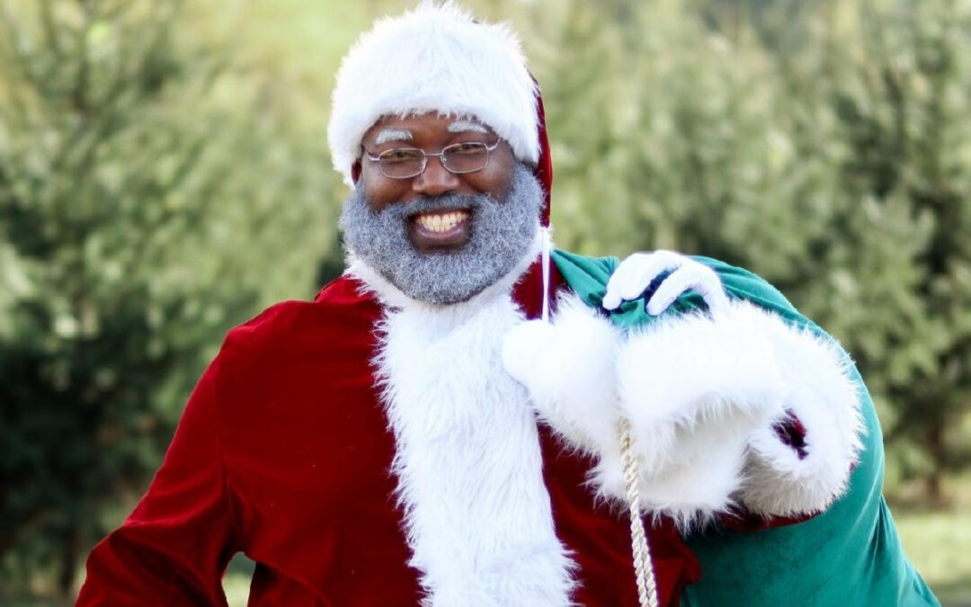 Santa Jason smiling with a green toy sack over his shoulder