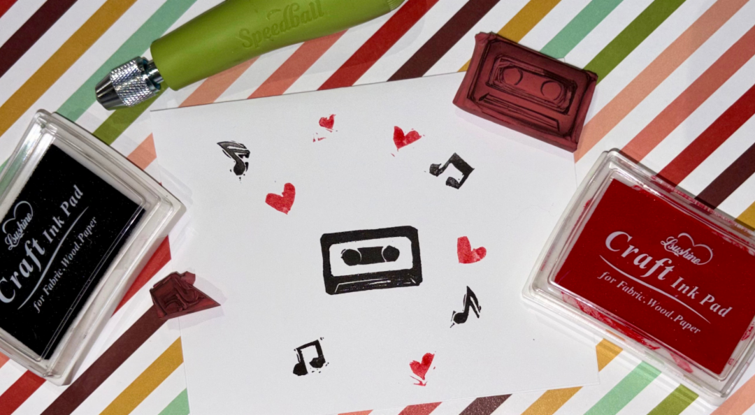 Ink pads, stamps, and a card printed with hearts, music notes, and a cassette tape