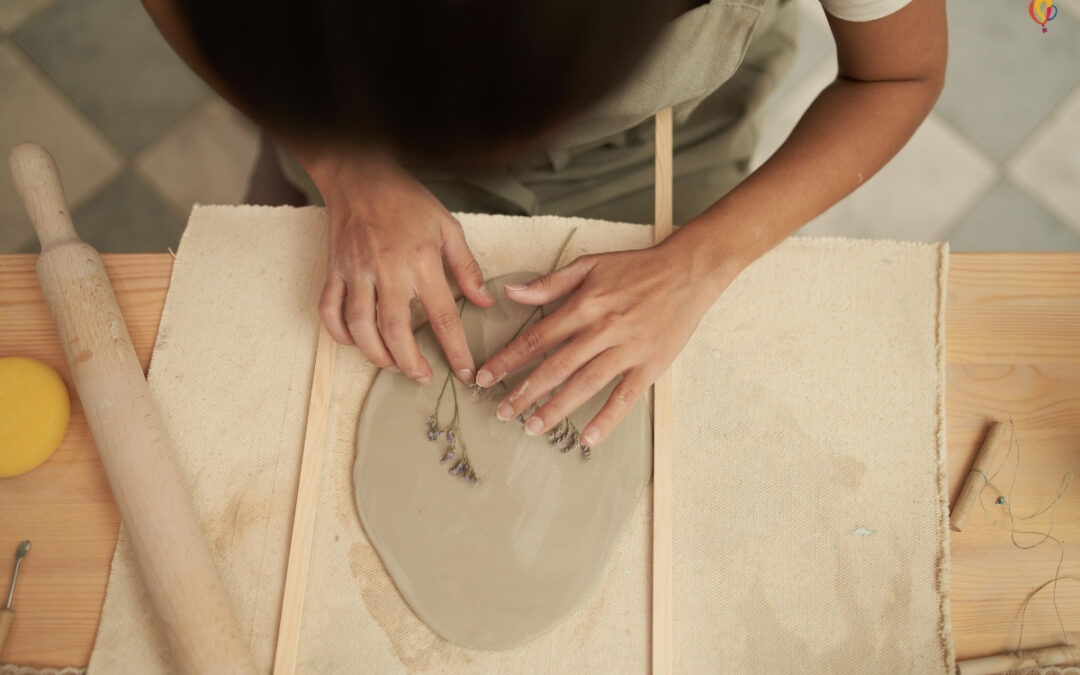 Woman pressing a flower into a slab of clay